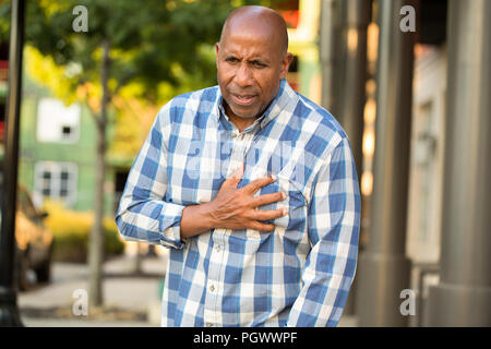 African American Man aventi i dolori tenendo il suo petto. Foto Stock