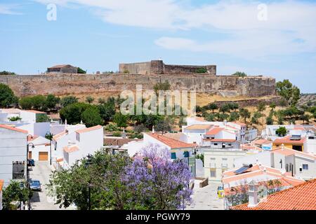 Vista in elevazione del castello e la città di edifici con una graziosa struttura Jacaranda in piena fioritura in primo piano, Castro Marim, Algarve, Portogallo, dell'Europa. Foto Stock