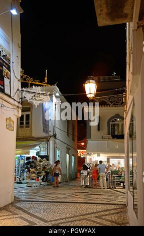 Via dello shopping nella città vecchia di notte con turisti che si godono la impostazione, Albufeira, Portogallo, Europa. Foto Stock