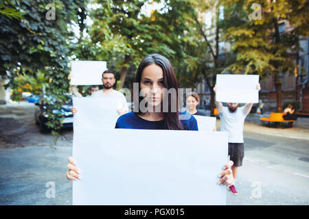 Gruppo di protesta dei giovani all'esterno. La protesta, persone, dimostrazione, democrazia, lotta, diritti, protestando concetto. La Caucasian uomini e womem holding vuoto poster o banner con spazio di copia Foto Stock