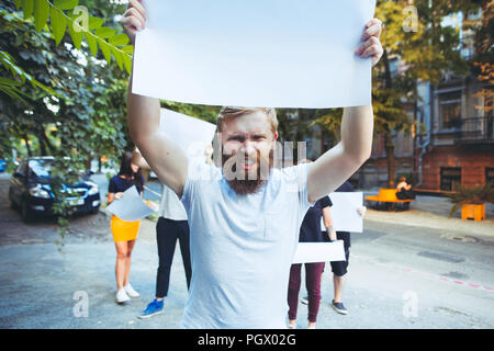 Gruppo di protesta dei giovani all'esterno. La protesta, persone, dimostrazione, democrazia, lotta, diritti, protestando concetto. La Caucasian uomini e womem holding vuoto poster o banner con spazio di copia Foto Stock