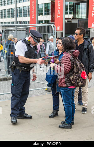 London, Regno Unito - 23 Maggio 2017: funzionario di polizia aiutare i turisti con informazioni vicino a Torre di Londra, Regno Unito, Europa occidentale. Foto Stock