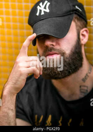 Ritratto di un giovane hipster tatuato uomo con New York Yankees hat Foto Stock