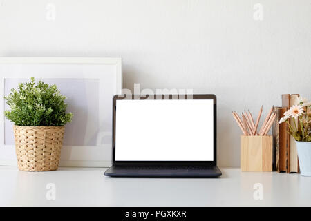 Area di lavoro scrivania da ufficio con computer portatile impianto e pentola a matita sul tavolo bianco, Mock up portatile schermo vuoto. Foto Stock