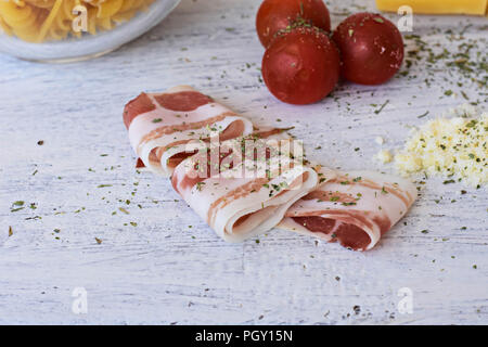 Ingredienti per la cottura- pancetta dolce ciliegie di pomodoro, formaggio, spaghetti-/ di pasta alimentare a sfondo di luce sullo sfondo di legno Foto Stock