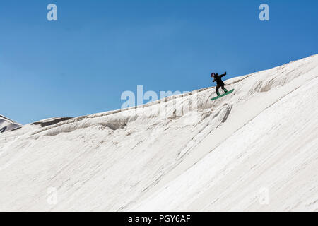 Una femmina di freeride snowboarder saltare da una scogliera e rende il suo trucco Foto Stock
