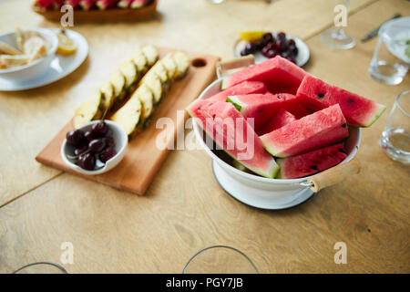 Fresche e mature di anguria in una terrina le ciliegie e fette di ananas servite sul tavolo preparato per gli ospiti Foto Stock