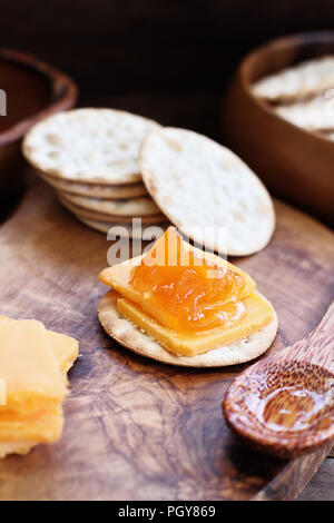 Acqua cracker e formaggio cheddar e salate fatte in casa vaniglia melone marmellata. Estrema profondità di campo con il fuoco selettivo su aperitivo in centro. Foto Stock