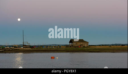 Una tranquilla serata estiva in basso di raggiungono il fiume Beaulieu con la luna piena sorge sullo spiedo di sabbia e la vela club edificio. Le colline di th Foto Stock