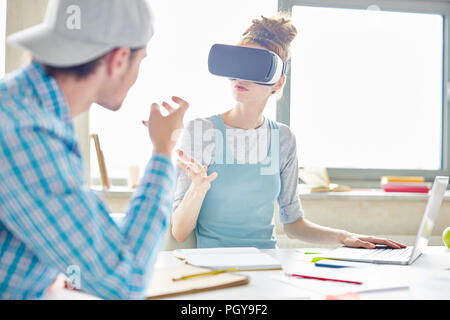 Occupato partner di avvio gesti delle mani mentre si discute il nuovo progetto, giovane donna in realtà virtuale occhiali che spiega la strategia a un collega Foto Stock