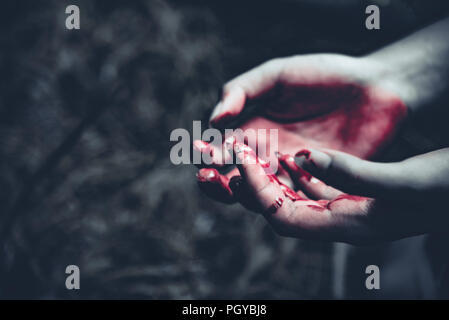 Close up di sanguinose mani nella foresta scuro dello sfondo. L' orrore e la nozione di Ghost. Penale e concetto di omicidio. Il giorno di Halloween e il sacrificio del tema. La gente di un Foto Stock