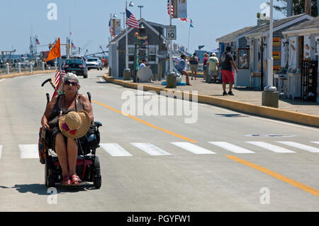 Femmina handicappati senior citizen tramite sedia elettrica in vacanza. Foto Stock