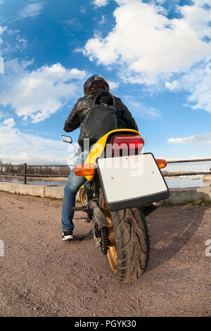 Ampio angolo di visione sul retro del giallo motociclista su moto con chiaro vuoto piastra di licenza Foto Stock