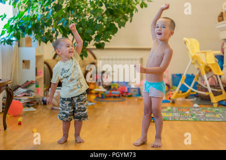 Due ragazzini sono a fare gli esercizi. Due bambini piccoli a casa facendo sport. I bambini fanno esercizi. Due ragazzini sono a fare gli esercizi. Il concetto di Foto Stock