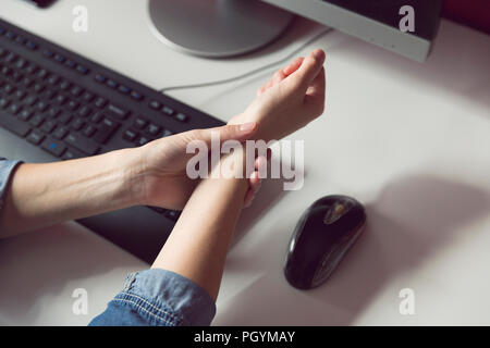 La sindrome di Office - Giovani donne che soffrono di dolori a mano mentre si utilizza il computer al lavoro. Professionali di fattore di rischio. Medico e sanitario concetto. Foto Stock