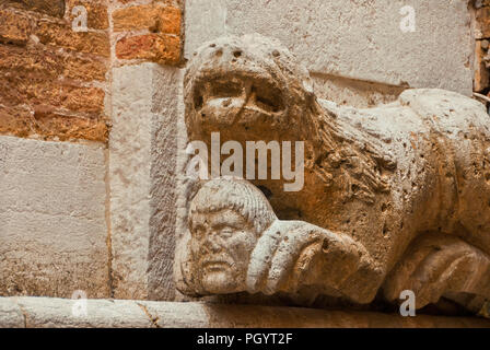 Lion o Monster tenendo testa umana con zampe, antica statua medievale su una parete nel centro storico di Venezia Foto Stock