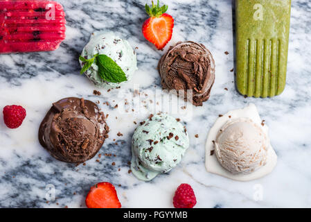 La selezione di diversi ice cream scoop come la menta, cioccolato e fragola su sfondo marmo, vista dall'alto Foto Stock