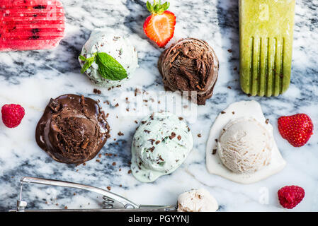 La selezione di diversi ice cream scoop come la menta, cioccolato e fragola su sfondo marmo, vista dall'alto Foto Stock