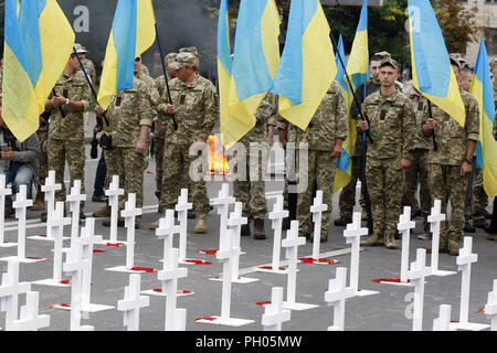 Kiev, Ucraina. Il 29 agosto, 2018. Combattenti ucraini sostare nelle vicinanze di croci con portrets di ucciso soldati ucraini, che erano stati persi in combattimenti nei pressi di Ilovaysk città quattro anni fa, durante una manifestazione di protesta di fronte l'Ambasciata russa a Kiev in Ucraina, il 29 agosto 2018. Gli ucraini riuniti in memoria di perdita di soldati ucraini, marcatura marcatura del quarto anniversario della lotta in Ilovaysk. Credito: ZUMA Press, Inc./Alamy Live News Foto Stock