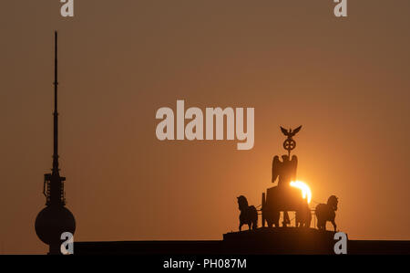 Berlino, Germania. Il 29 agosto, 2018. La Porta di Brandeburgo e la torre della televisione può essere visto solo come una silhouette contro il Rising Sun. Credito: Paolo Zinken/dpa/Alamy Live News Foto Stock