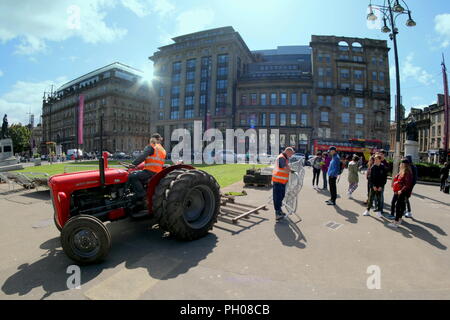 Glasgow, Scotland, Regno Unito. 29 Agosto, 2018. Ora di pranzo gli ospiti sono stati trattati per un po' di storia vivente come un classico rosso 1964 Massey Ferguson 35X trattore è apparso nella città del George Square. La gente del posto e i turisti hanno guardato come il tappeto erboso che è stato sollevato per il recente Campionato Europeo accogliente centro è stato sostituito. Il modello Sport insoliti ruote doppie per aumentare la trazione e è stata modificata dal proprietario fiero nella foto. Gerard Ferry/Alamy news Foto Stock