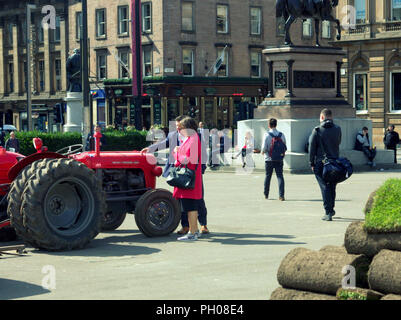 Glasgow, Scotland, Regno Unito. 29 Agosto, 2018. Ora di pranzo gli ospiti sono stati trattati per un po' di storia vivente come un classico rosso 1964 Massey Ferguson 35X trattore è apparso nella città del George Square. La gente del posto e i turisti hanno guardato come il tappeto erboso che è stato sollevato per il recente Campionato Europeo accogliente centro è stato sostituito. Il modello Sport insoliti ruote doppie per aumentare la trazione e è stata modificata dal proprietario fiero nella foto. Gerard Ferry/Alamy news Foto Stock