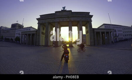 Berlino, Germania. Il 29 agosto, 2018. Un driver di scooter gode il sunrise presso la Porta di Brandeburgo. Credito: Paolo Zinken/dpa/Alamy Live News Foto Stock