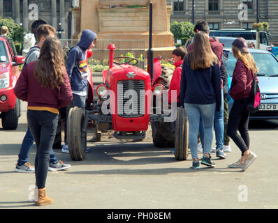 Glasgow, Scotland, Regno Unito. 29 Agosto, 2018. Ora di pranzo gli ospiti sono stati trattati per un po' di storia vivente come un classico rosso 1964 Massey Ferguson 35X trattore è apparso nella città del George Square. La gente del posto e i turisti hanno guardato come il tappeto erboso che è stato sollevato per il recente Campionato Europeo accogliente centro è stato sostituito. Il modello Sport insoliti ruote doppie per aumentare la trazione e è stata modificata dal proprietario fiero nella foto. Gerard Ferry/Alamy news Foto Stock