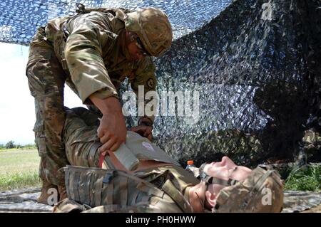 Primo Lt. Jayde Unasa, un fante assegnati al 2° Battaglione, 35th Reggimento di Fanteria, 3° Brigata Team di combattimento, XXV divisione di fanteria, esegue il primo aiuto per una ferita addominale aperta durante l esperto di badge Fante test a Schofield Barracks, Hawaii, il 14 giugno 2018. Fanti in tutto il venticinquesimo ID partecipano a questo evento biennale per guadagnare il prestigioso esperto Fantassin Badge. Foto Stock