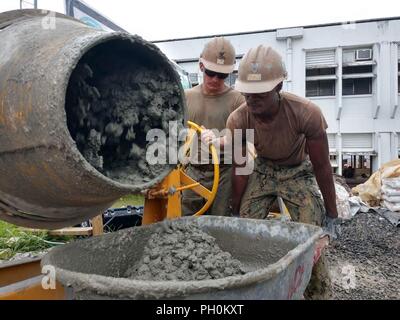 CHUUK, Stati Federati di Micronesia (Giugno 14th, 2018) Builder 2a classe Thomas Jobe, sinistra e Utilitiesman 2a classe Rien Johnson Esquire, assegnato alla Naval Mobile Battaglione di costruzione (NMCB) 11, Costruzione azione civica dettaglio Stati Federati di Micronesia, riempire una carriola con cemento. NMCB-11 è distribuito per eseguire la costruzione, umanitari e di assistenza estera, il teatro e la cooperazione in materia di sicurezza nel VII flotta area di operazioni. Foto Stock