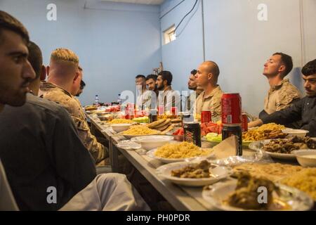 Provincia di Helmand, Afghanistan (16 giugno 2018) - USA Marines con la Task Force Southwest (TFSW) ascoltare Col. Shah Wali, comandante della 215th Corps militare regionale Centro di formazione, dare un discorso durante un'Eid al-Fitr pasto presso il Camp Shorabak. Esercito Nazionale Afghano 215th Corps soldati degli Stati Uniti ha invitato i membri del servizio con TFSW per condividere in uno dei la maggior parte delle feste religiose nell Islam Eid al-Fitr, che celebra la conclusione di circa trenta giorni di alba a crepuscolo il digiuno durante il Ramadan. Foto Stock