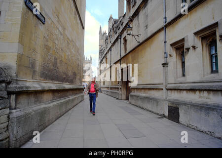 Uomo che cammina nel vialetto tra due edifici, Oxford, Oxfordshire, England, Regno Unito Foto Stock