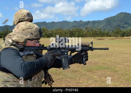 Un membro dell'Università delle Hawaii a Manoa Rainbow Warriors football coaching incendi personale un m4 carbine durante un live fire esercizio a Schofield Barracks, Hawaii, il 23 giugno 2018. Il XXV divisione di fanteria ha ospitato il Rainbow Warrior per un team building giorno che ha coinvolto il personale di coaching in un live drill incendio e i giocatori alla leadership corso di reazione e la fiducia di corso. Foto Stock