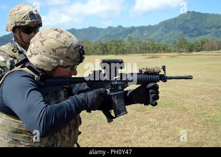 Un membro dell'Università delle Hawaii a Manoa Rainbow Warriors football coaching incendi personale un m4 carbine durante un live fire esercizio a Schofield Barracks, Hawaii, il 23 giugno 2018. Il XXV divisione di fanteria ha ospitato il Rainbow Warrior per un team building giorno che ha coinvolto il personale di coaching in un live drill incendio e i giocatori alla leadership corso di reazione e la fiducia di corso. Foto Stock