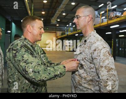Supporto navale attività BAHRAIN (25 giugno 2018) DEGLI STATI UNITI Navy Cmdr. Daniel Brown, Naval Amphibious vigore, Task Force 51/5th Marine Expeditionary Brigade direttore della Direzione Logistica, presenta U.S. Master Marine Sgt. William J. Tolleson con il servizio meritevole medaglia (stella d'oro al posto della seconda award) per il suo eccellente servizio meritorio mentre serve come contratto operativo capo di supporto da luglio 2016 a giugno 2018. Come il comando del contraente solitario esperto ha negoziato e gestito il supporto di vita e il supporto di contratti a sostegno di ansiosi Lion 2017 e 2018 per salvare il comando o Foto Stock