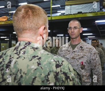 Supporto navale attività BAHRAIN (25 giugno 2018) DEGLI STATI UNITI Navy Cmdr. Daniel Brown, Naval Amphibious vigore, Task Force 51/5th Marine Expeditionary Brigade direttore della Direzione Logistica, presenta U.S. Master Marine Sgt. William J. Tolleson con il servizio meritevole medaglia (stella d'oro al posto della seconda award) per il suo eccellente servizio meritorio mentre serve come contratto operativo capo di supporto da luglio 2016 a giugno 2018. Come il comando del contraente solitario esperto ha negoziato e gestito il supporto di vita e il supporto di contratti a sostegno di ansiosi Lion 2017 e 2018 per salvare il comando o Foto Stock
