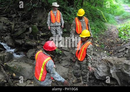 Il personale Sgt. Gedeone Hurtault, ingegnere 662nd Supporto Azienda, spiega al comandante del battaglione, il Mag. Nina Clarke-Brewley il lavoro il suo team ha fatto per sostituire un canale sotterraneo a Camp Dawson, West Virginia Giugno 21. 104Th truppa personale di comando e le Isole Vergini Guardia nazionale capo del personale Col. Shawn Harris ha visitato l'azienda mentre sulla formazione annuale. Foto Stock