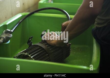 Sgt. Zachary Khordi utilizza un tubo flessibile a spruzzo per spruzzare un mezzo tattico di sostituzione del veicolo MK23 standard carrello carico essiccatore di aria in un serbatoio di solvente a Camp Kinser, Okinawa, in Giappone, 26 giugno 2018. Khordi, un automotive tecnico di manutenzione con il motore di trasporto e impresa di manutenzione, esegue la manutenzione preventiva su veicoli per mantenere l'integrità dei veicoli è intatto e garantire la sicurezza dei conducenti e dei loro occupanti. Khordi è un nativo di Cliffwood, New Jersey. Foto Stock