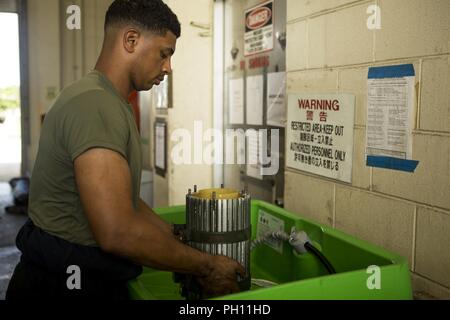 Sgt. Zachary Khordi lavaggi un mezzo tattico di sostituzione del veicolo MK23 standard carrello carico essiccatore di aria in un serbatoio di solvente a Camp Kinser, Okinawa, in Giappone, 26 giugno 2018. Khordi, un automotive tecnico di manutenzione con il motore di trasporto e impresa di manutenzione, esegue la manutenzione preventiva su veicoli per mantenere l'integrità dei veicoli è intatto e garantire la sicurezza dei conducenti e dei loro occupanti. Khordi è un nativo di Cliffwood, New Jersey. Foto Stock