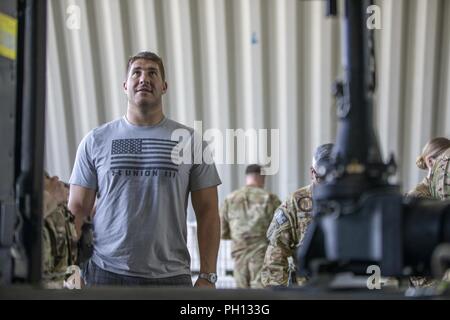 La National Football League Atlanta Falcons' centro Alex Mack, osserva un esercito spagnolo aeromobile durante una visita a Camp Taji, Iraq, 18 giugno 2018. Taji Camp è uno dei quattro Combined Joint Task Force- operazione inerente risolvere la costruzione di capacità del partner location dedicate ai partner di formazione delle forze e il miglioramento della loro efficacia sul campo di battaglia. Foto Stock