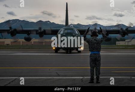 Un Giappone Aria forza di autodifesa Airman esegue il marshalling di un JASDF C-130H Hercules aeromobile da Hamamatsu Air Base, Giappone, prima del decollo durante il Red Flag-Alaska 18-2 operazioni alla base comune Elmendorf-Richardson, Alaska, 21 giugno 2018. Settantasette JASDF aviatori azionato fuori JBER per Pacific Air Forces " premier air combat esercizio. Sin dal suo inizio, migliaia di service membri provenienti da tutti i rami del militare degli Stati Uniti, nonché servizi armati di diversi paesi di tutto il mondo hanno preso parte in rosso Flag-Alaska. Foto Stock