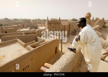 Amadou Cissé, una guida, guarda le tradizionali case di fango di Djenné, un sito Patrimonio Mondiale dell'Unesco. Mali, Africa occidentale Foto Stock