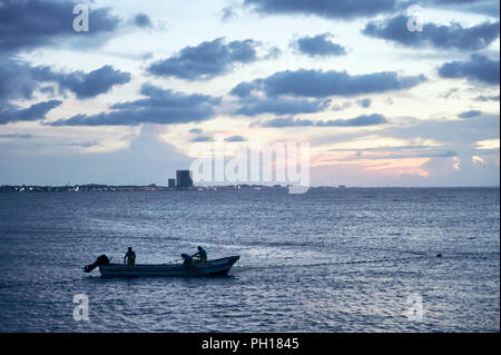 Queretaro, ver/MESSICO - Agosto 25, 2018: tre pescatori raccogliendo i loro cast net al tramonto, la città costiera di sullo sfondo Foto Stock