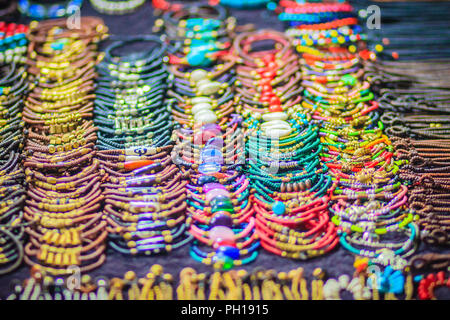 Braccialetti colorati, perline e collane souvenir in vendita su strada a Khao San Road mercato notturno, Bangkok, Thailandia. Foto Stock