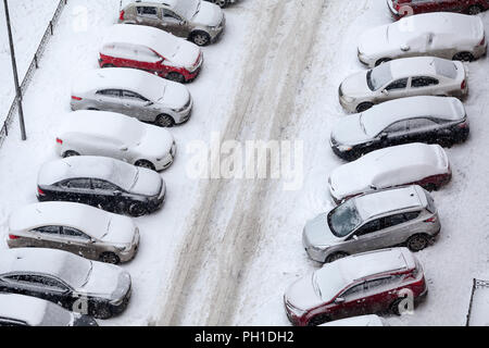 Vista da sopra a levarsi in piedi nelle linee snow-auto coperti in altri lati della strada sdrucciolevole, inverno parcheggio vicino all'edificio Foto Stock