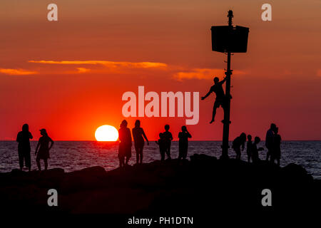 Le persone si mettono sul pontile, alcune attività di pesca e guardare il tramonto a Menemsha Beach in Chilmark, Massachusetts di Martha's Vineyard. Foto Stock