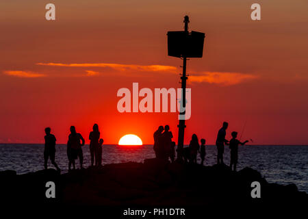 Le persone si mettono sul pontile, alcune attività di pesca e guardare il tramonto a Menemsha Beach in Chilmark, Massachusetts di Martha's Vineyard. Foto Stock