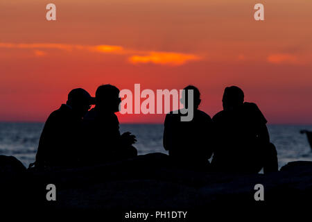 Persone sedersi sul molo dopo aver guardato il tramonto del vigneto del suono a Menemsha Beach in Chilmark, Massachusetts di Martha's Vineyard. Foto Stock