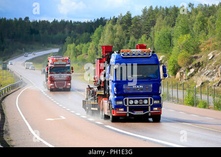 Orivesi, Finlandia - 27 agosto 2018: due semi carrelli di trasporto macchinari pesanti su strada bagnata in Finlandia centrale in un giorno di pioggia di fine estate. Foto Stock