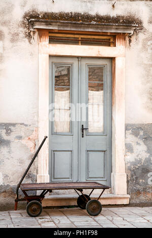 Vecchio vintage porte di entrata con rusty carrello nella parte anteriore di ingresso. Foto Stock